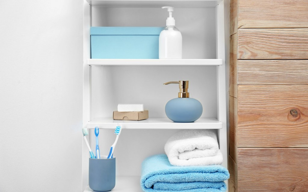 Towels, toiletries and soap dispenser sit on open shelves in a bathroom