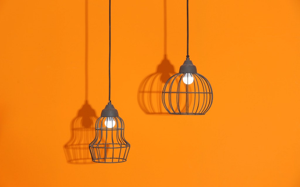 Two pendant lights hanging in front of an orange wall