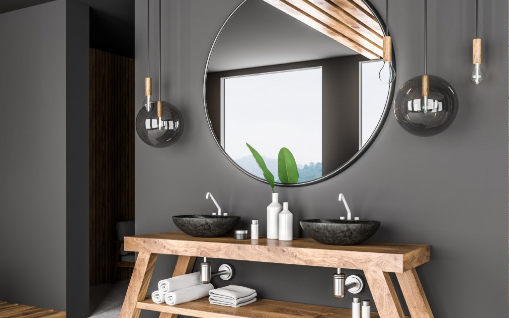 A big round mirror hangs above double bathroom sink 